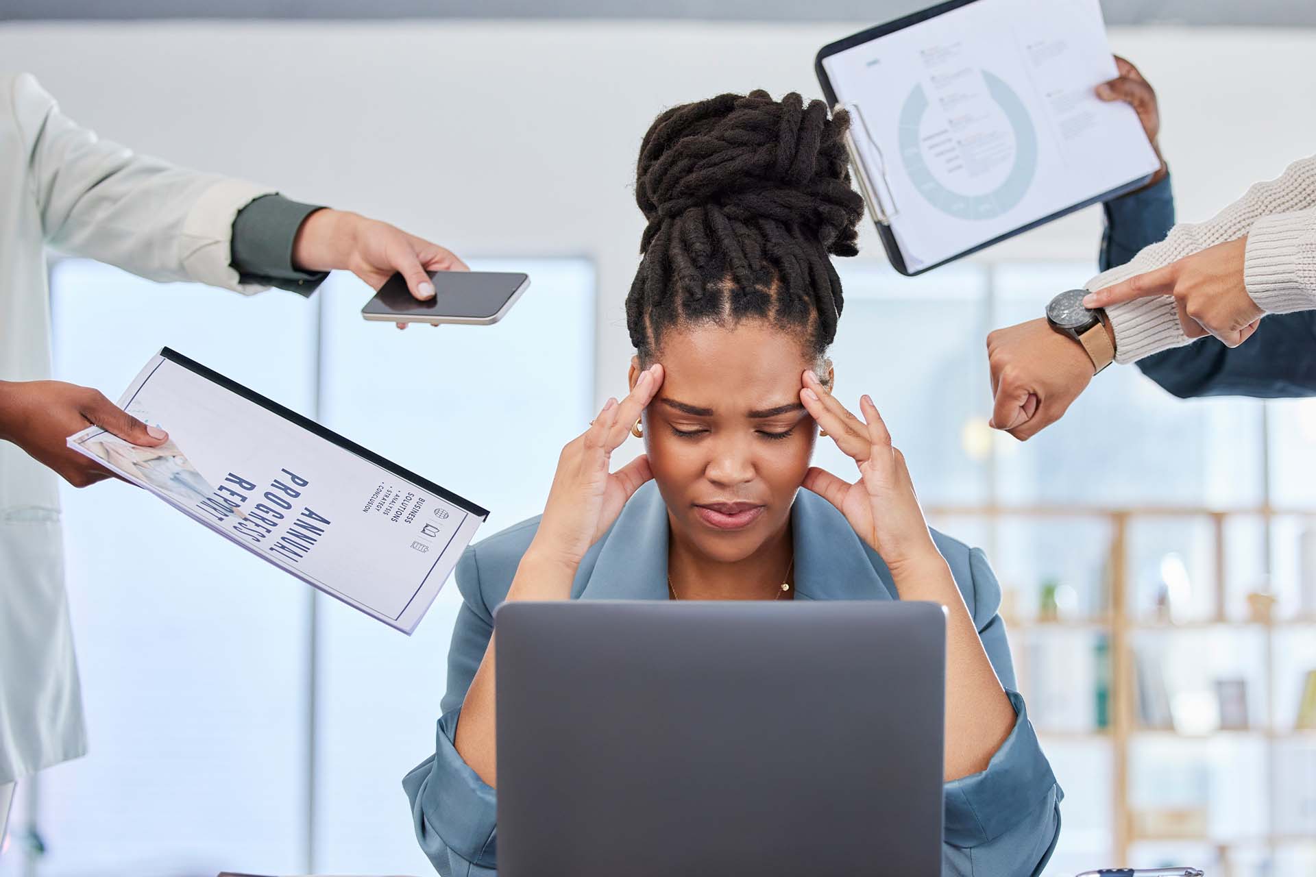 A stressed woman at her desk surrounded by people presenting her with documents, phone, and pointing at the time, illustrating workplace pressure and feedback anxiety.