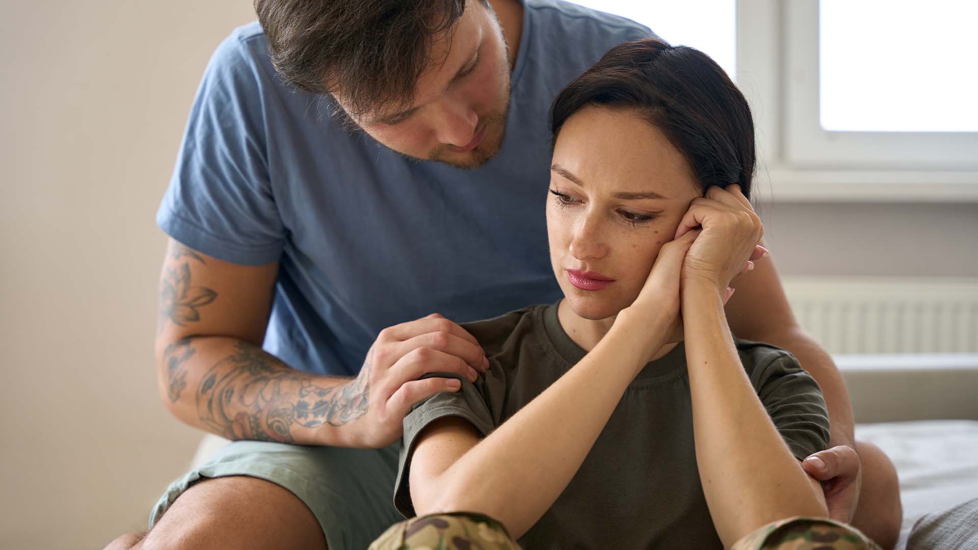 Man comforting a distressed woman in military attire, symbolizing the different types of trauma and the support needed for recovery