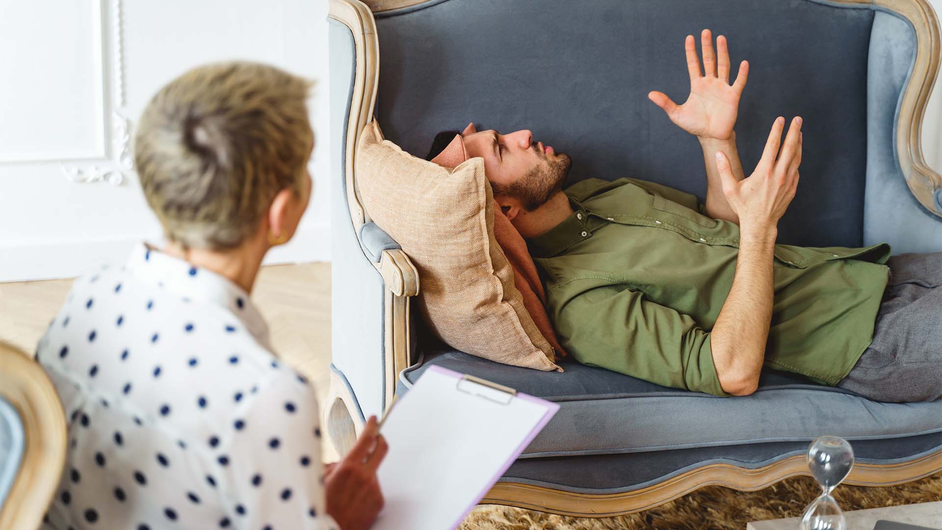 A man lying on a couch during an ISTDP session, passionately expressing emotions while the therapist listens attentively and takes notes.