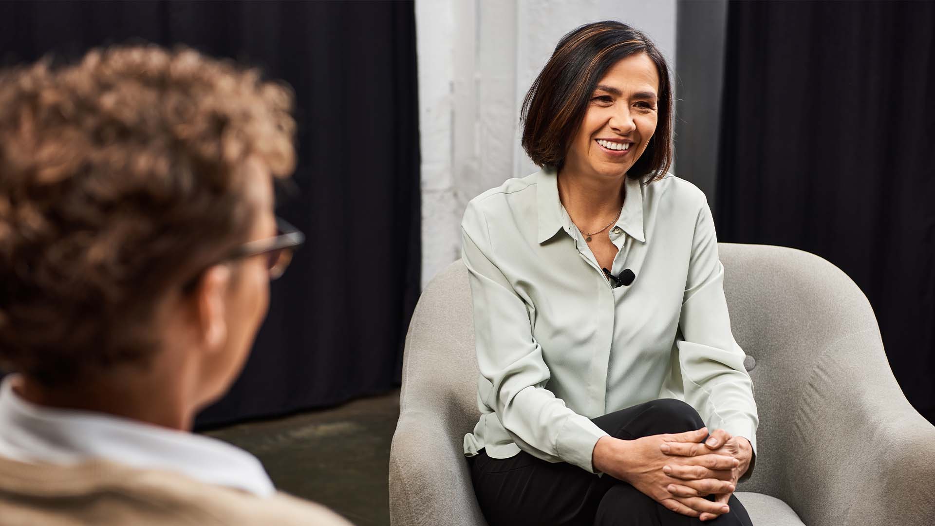 A therapist smiling warmly while engaging in a meaningful conversation during a logotherapy session, helping a client explore purpose and emotional well-being.