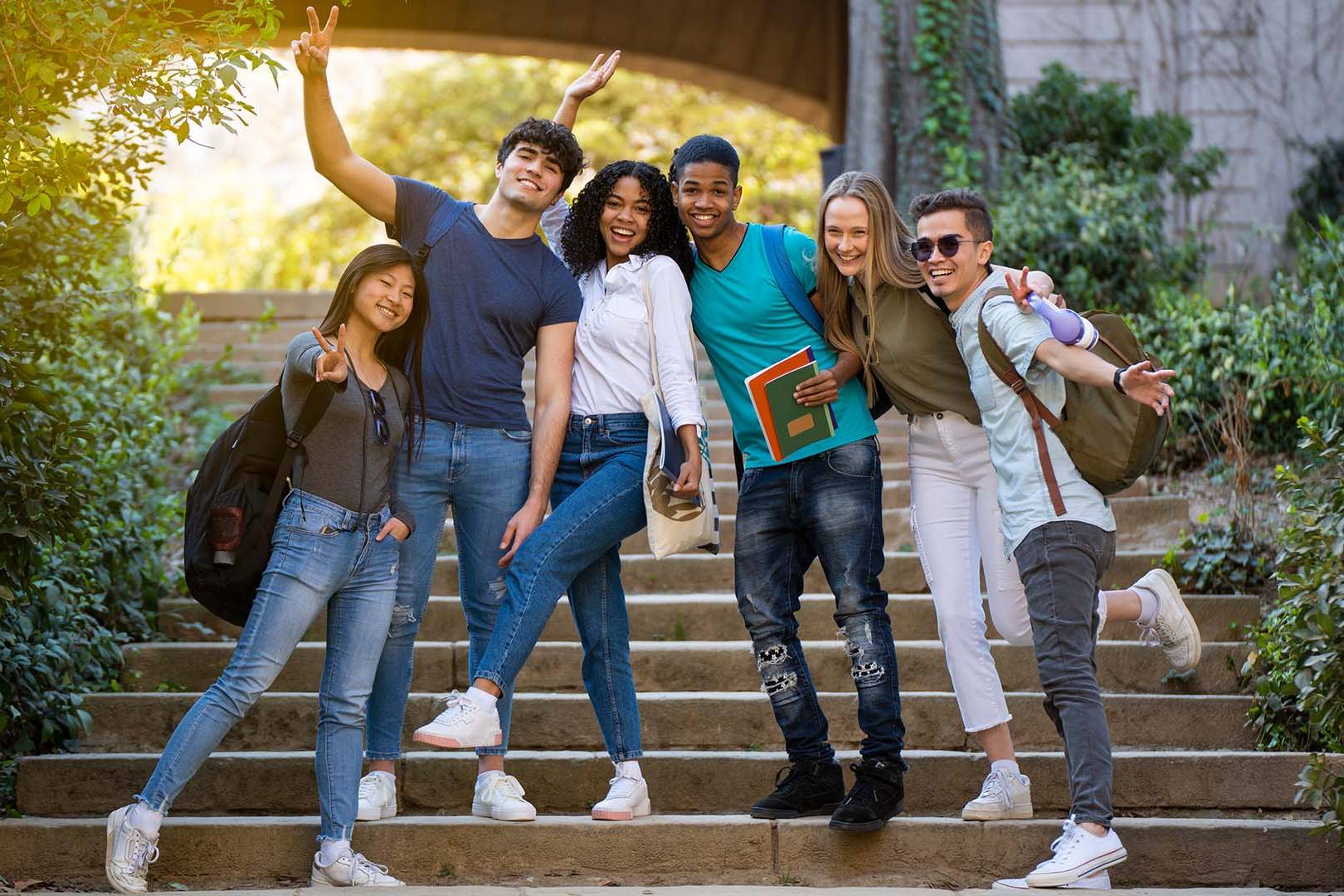 A diverse group of college students smiling and posing outdoors on campus steps, symbolizing connection, well-being, and academic success.