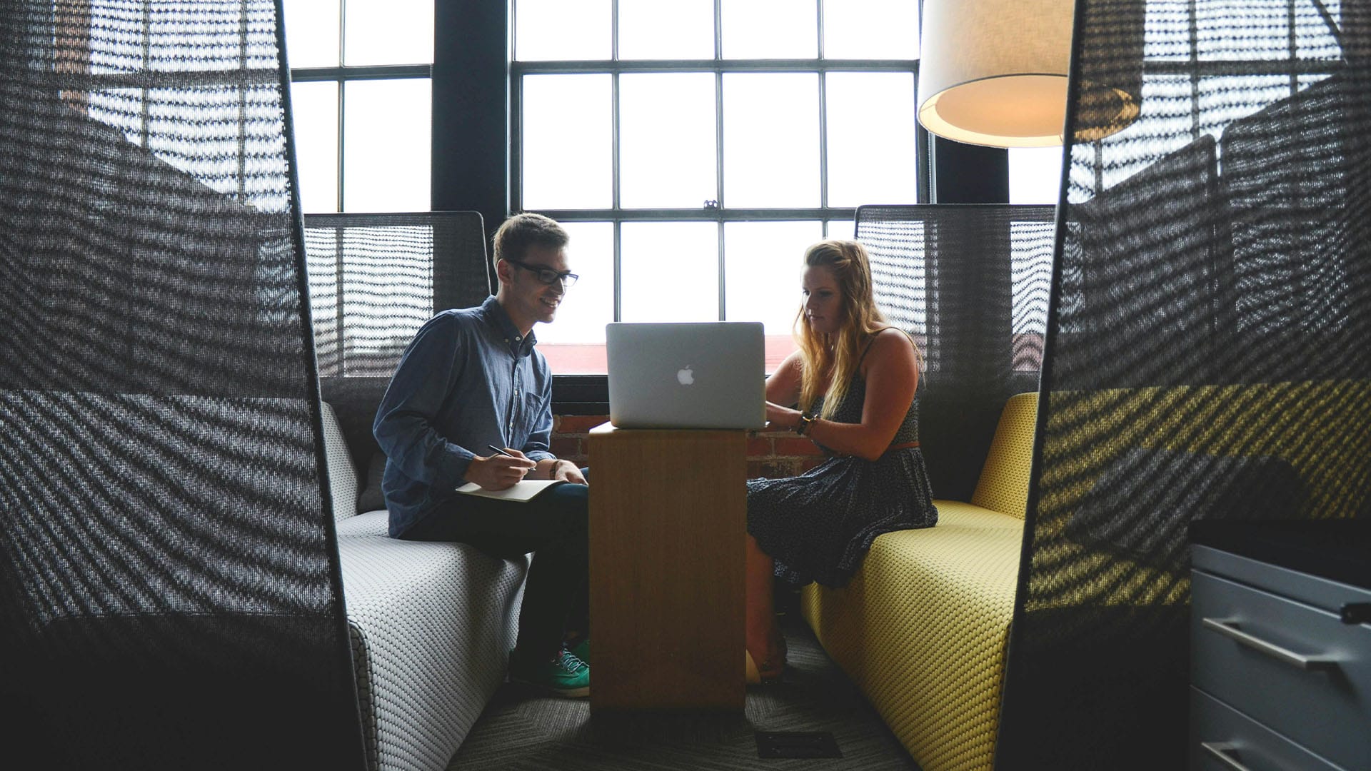 Man and woman seated in a modern, semi-private office nook, working together on a laptop—symbolizing post-divorce self-worth rebuilding through therapy.
