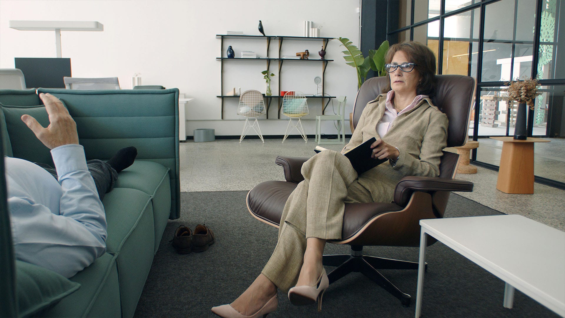 A therapist attentively listens and takes notes as a client shares during a private-pay therapy session in a modern office setting.
