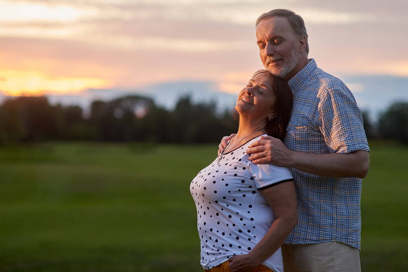 Older couple embracing outdoors at sunset, enjoying renewed connection after marriage and family therapy.
