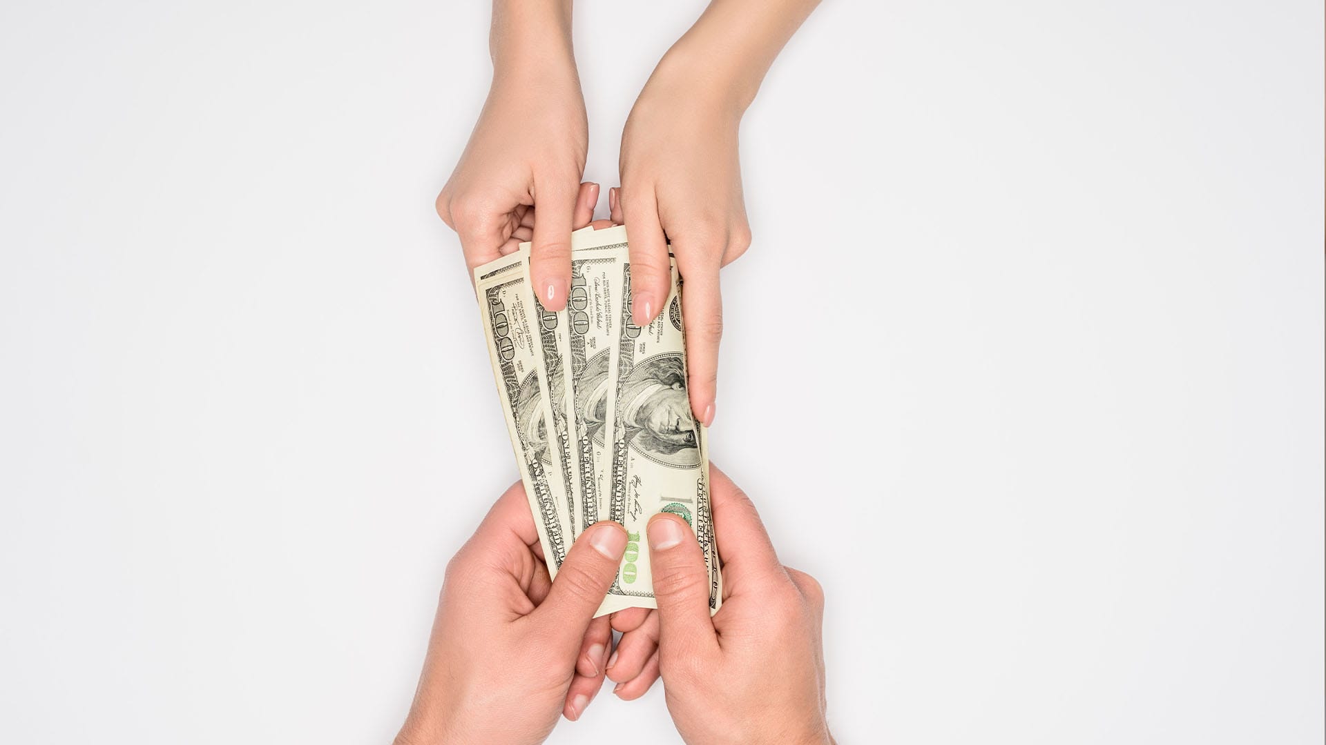 Close-up of hands exchanging U.S. hundred-dollar bills, representing the cost of private pay therapy in California for anxiety treatment.