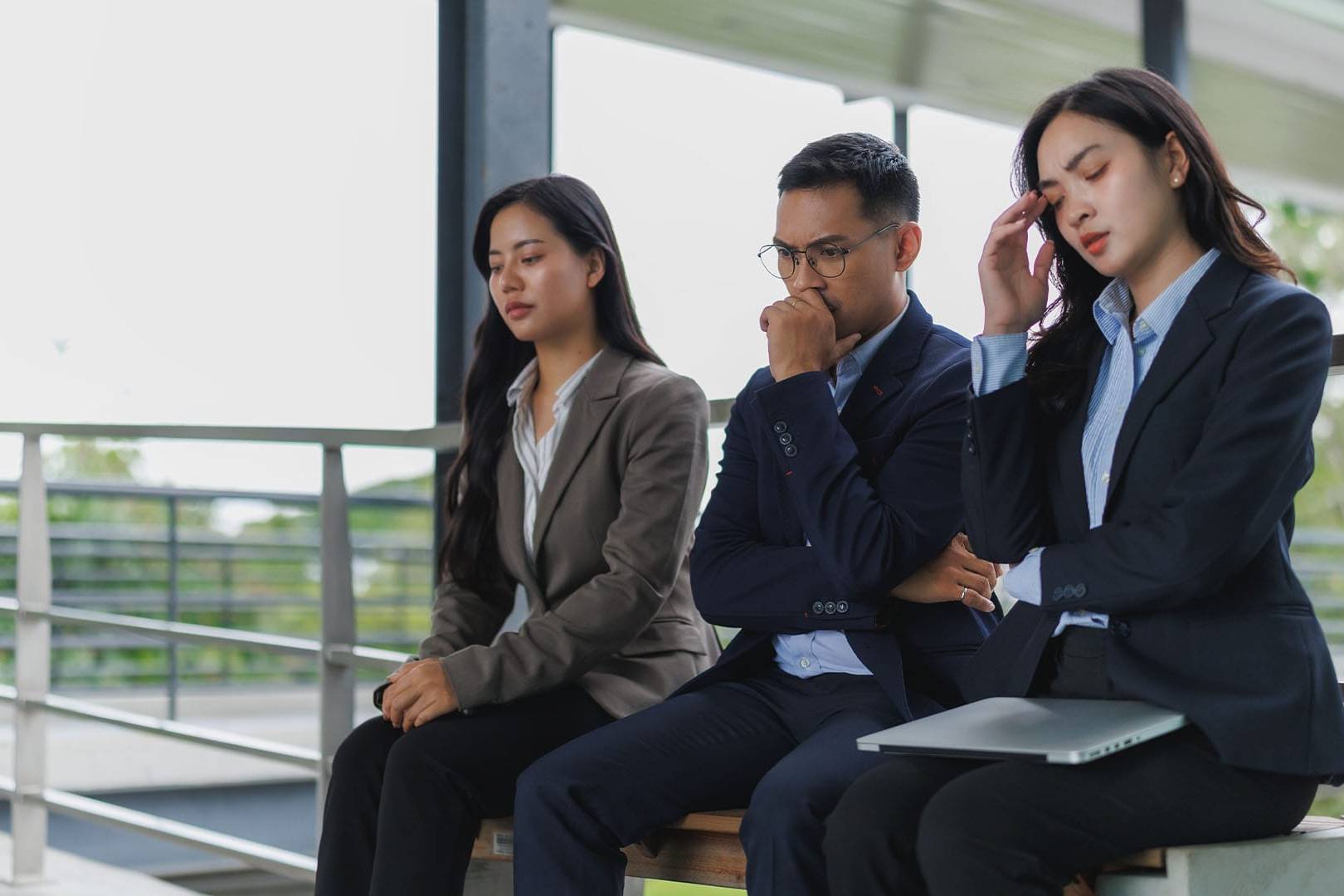 Stressed business professionals sitting on a bench, symbolizing overthinking, anxiety, and control issues that affect mental health.