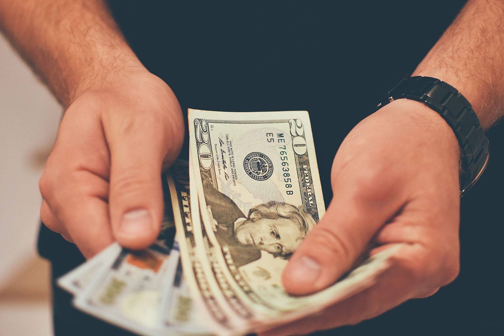 Close-up of a person holding U.S. dollar bills, symbolizing the cost of private counseling for stress and burnout in California.
