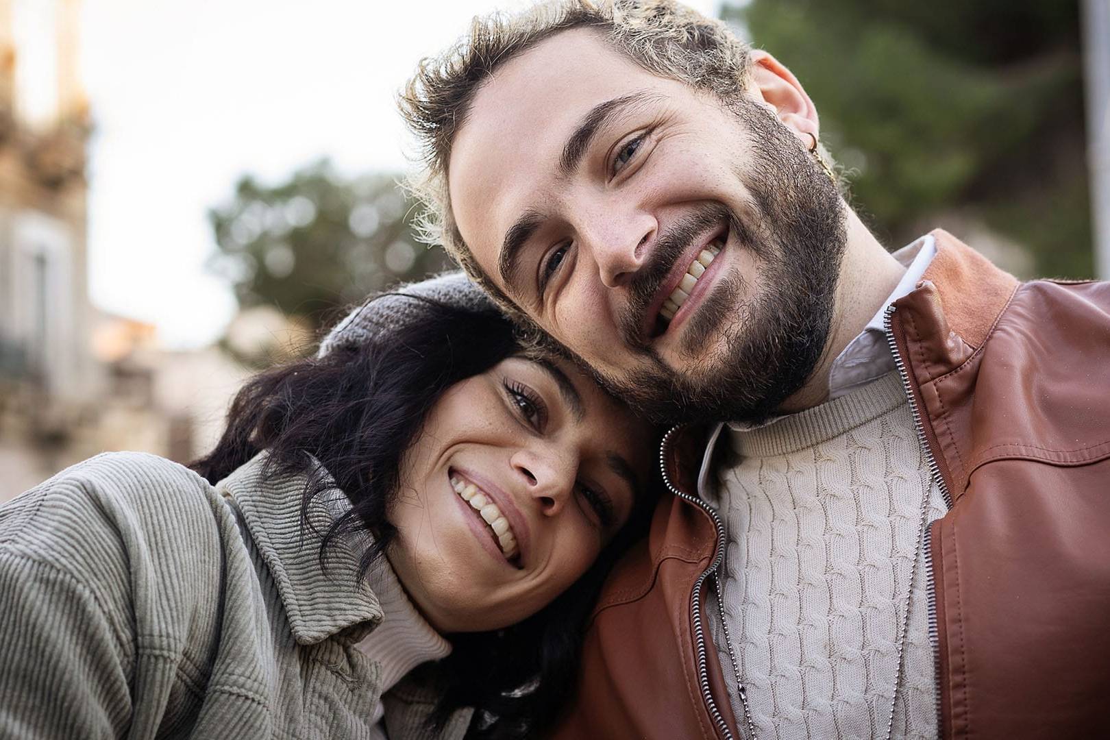 Smiling couple leaning their heads together outdoors, looking happy and connected