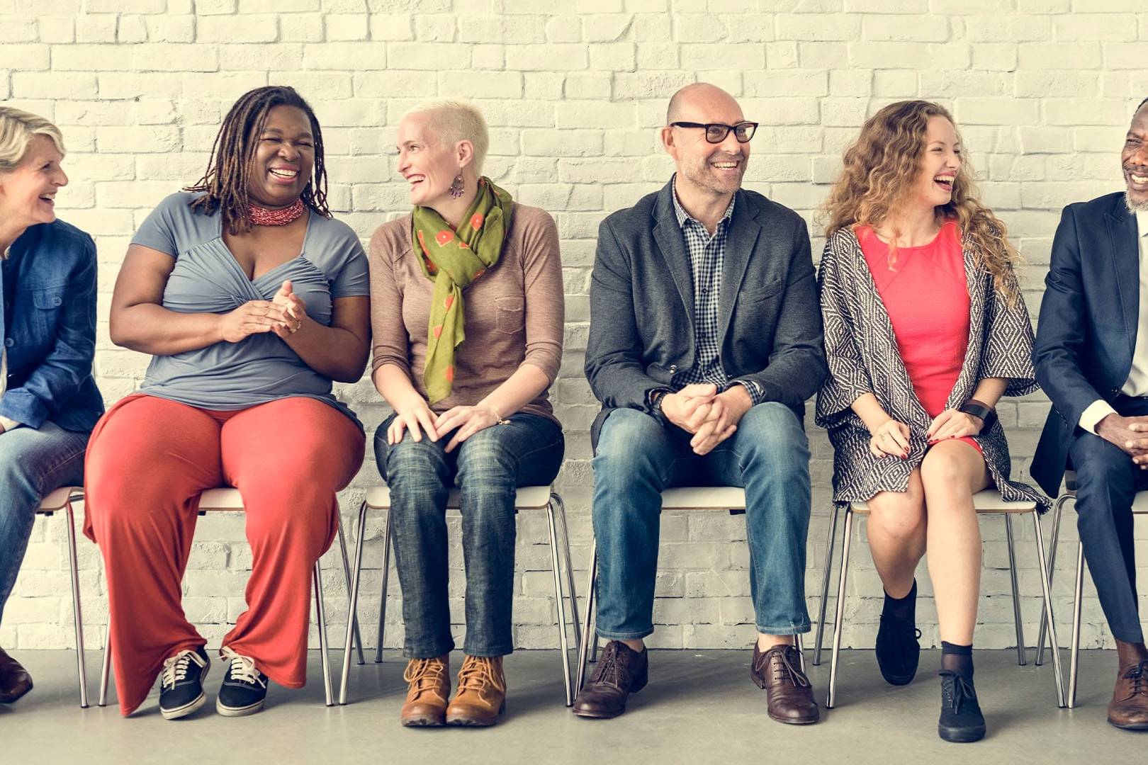 Diverse group of people smiling and talking while seated, representing top-rated private pay therapists in California for affluent clients.