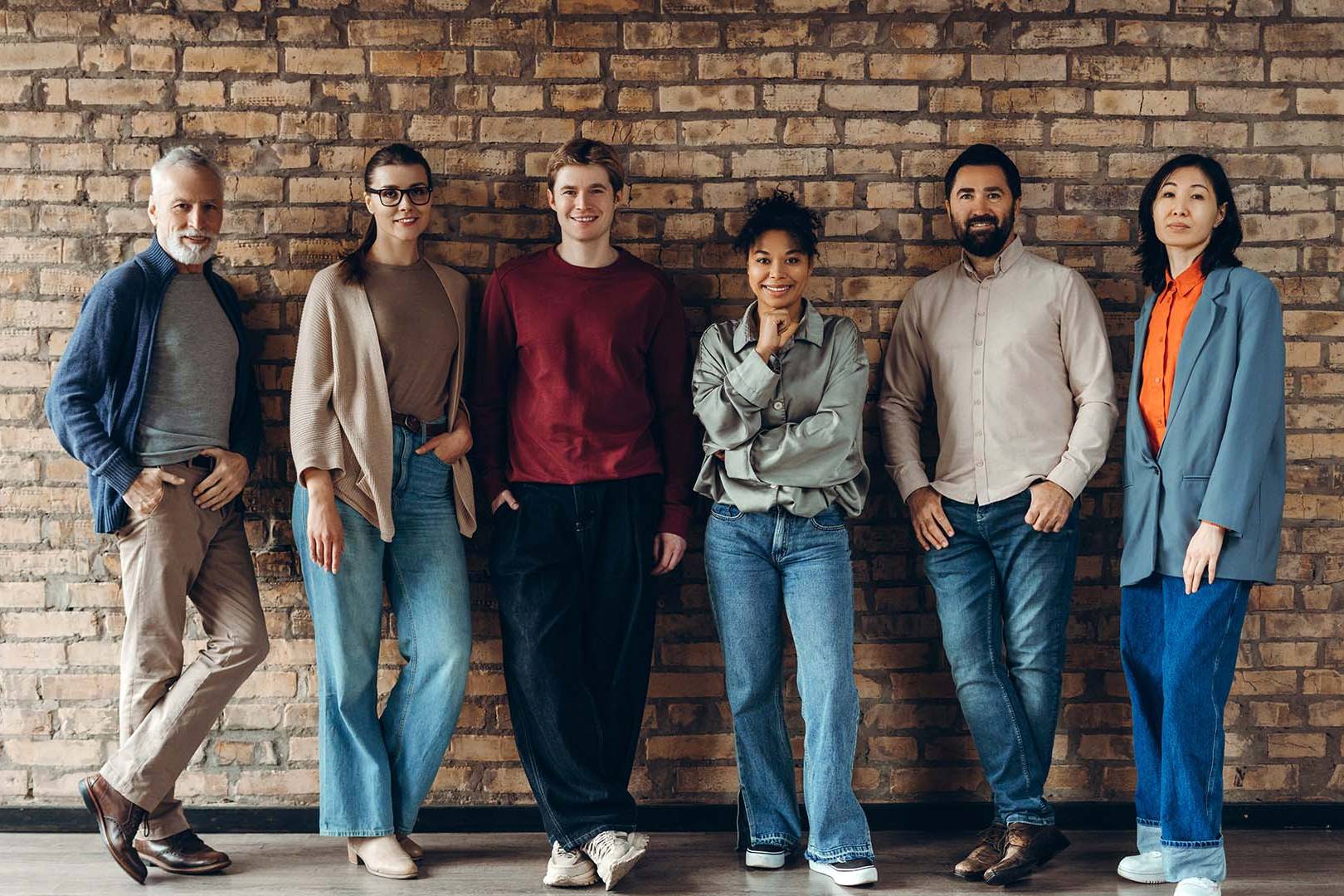 Online therapy for startup founders in California — diverse group of professionals standing together confidently against a brick wall.