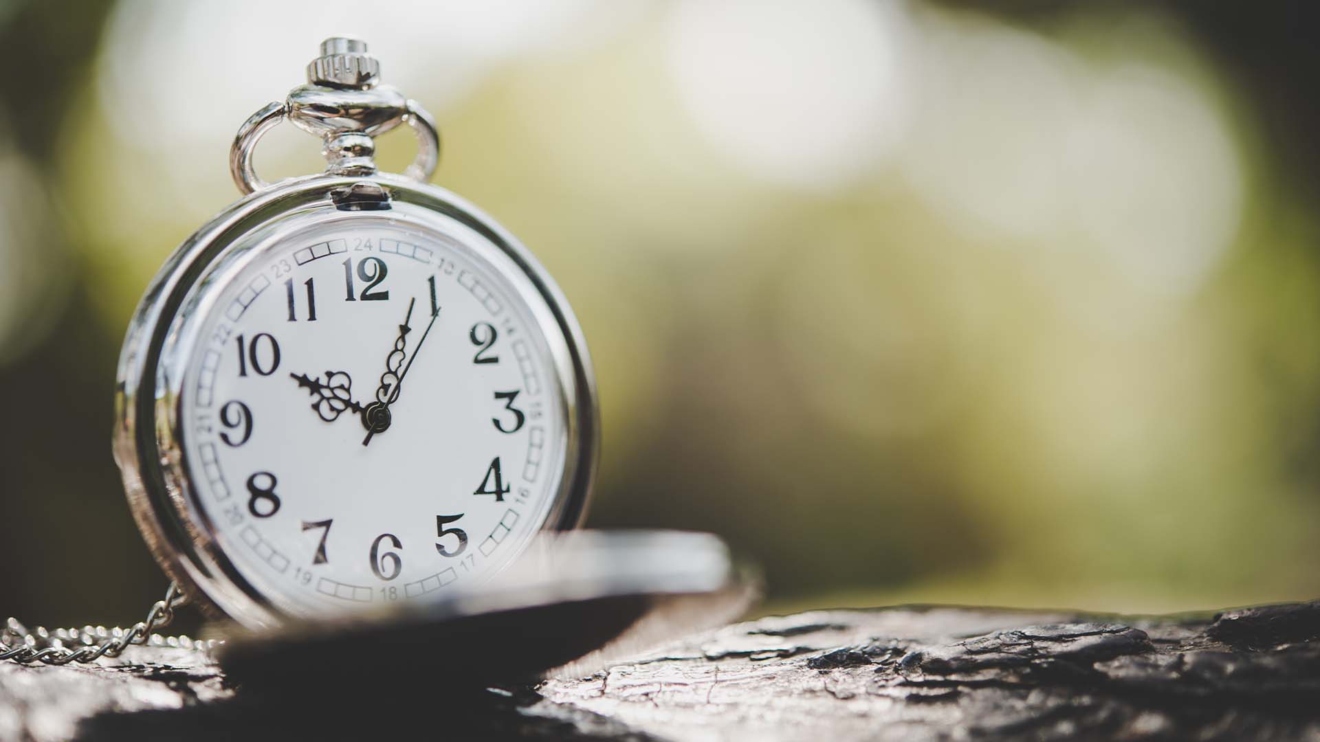 Vintage silver pocket watch resting on dark wood, symbolizing the focused time of a 3-hour therapy intensive session.