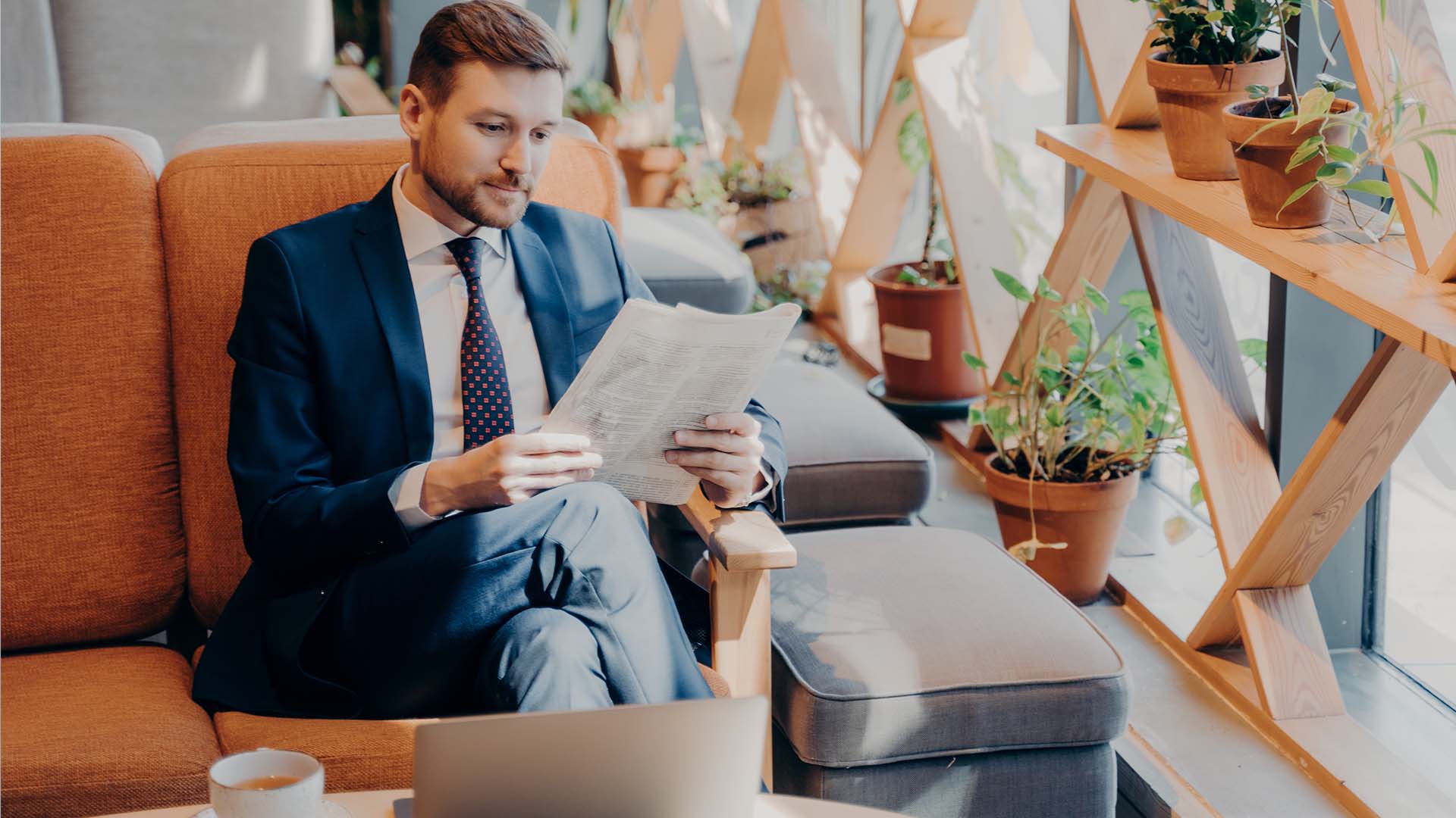 CEO in business suit reading documents in comfortable Los Angeles therapy office, representing specialized mental health support for chief executives