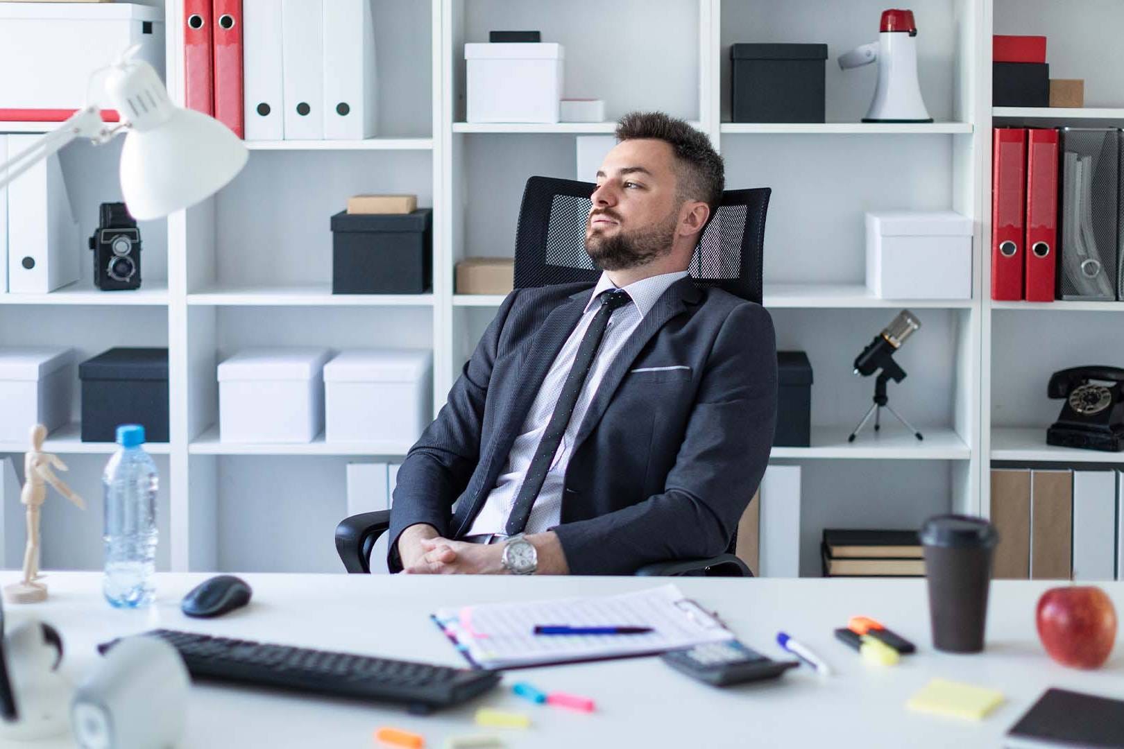 Exhausted executive leaning back in office chair showing decision fatigue and mental exhaustion from high-stakes leadership decisions