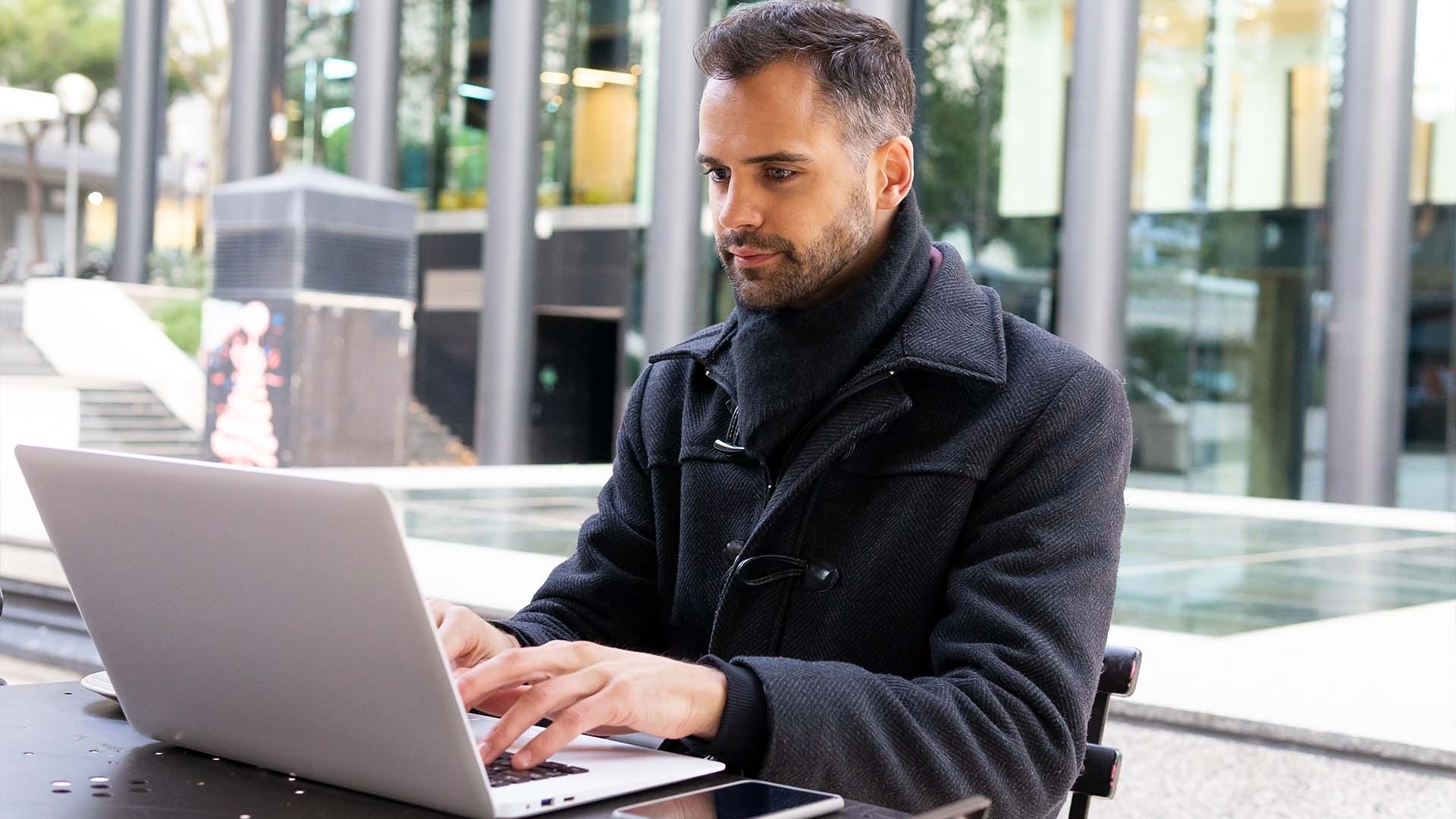Contemplative company leader working on laptop outdoors representing invisible mental health pressures of executive leadership requiring therapy