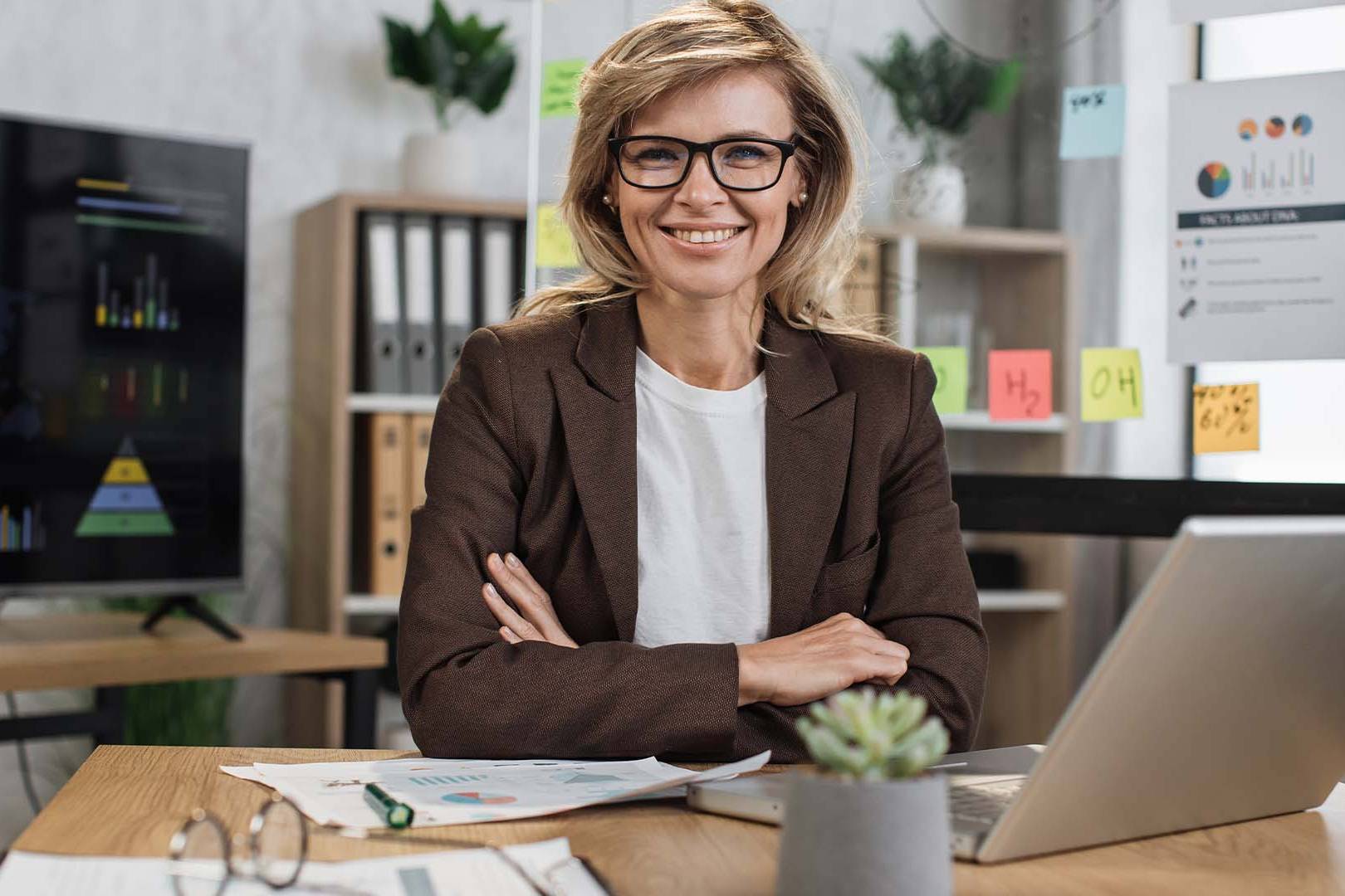 Confident female law firm partner in professional office setting with legal documents and screens, representing senior attorneys seeking private mental health support