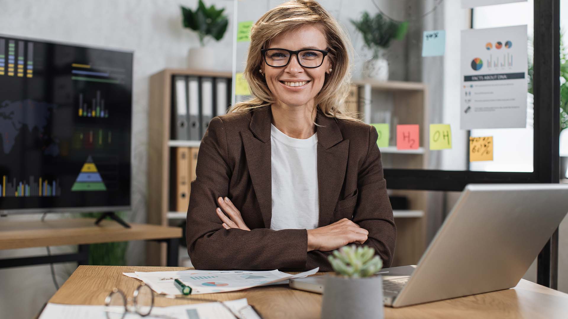 Confident female law firm partner in professional office setting with legal documents and screens, representing senior attorneys seeking private mental health support