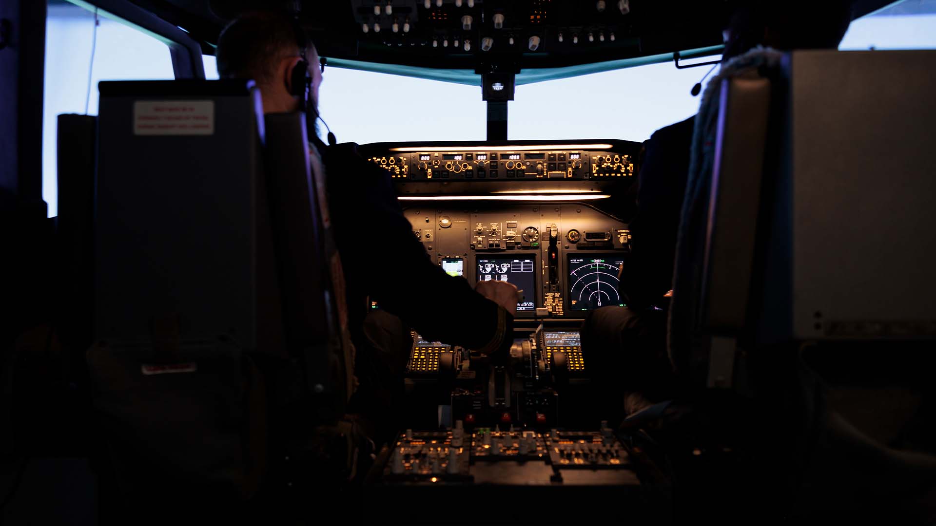 Two airline pilots in cockpit with illuminated instruments at night, representing pilots seeking confidential mental health support without FAA medical certification concerns