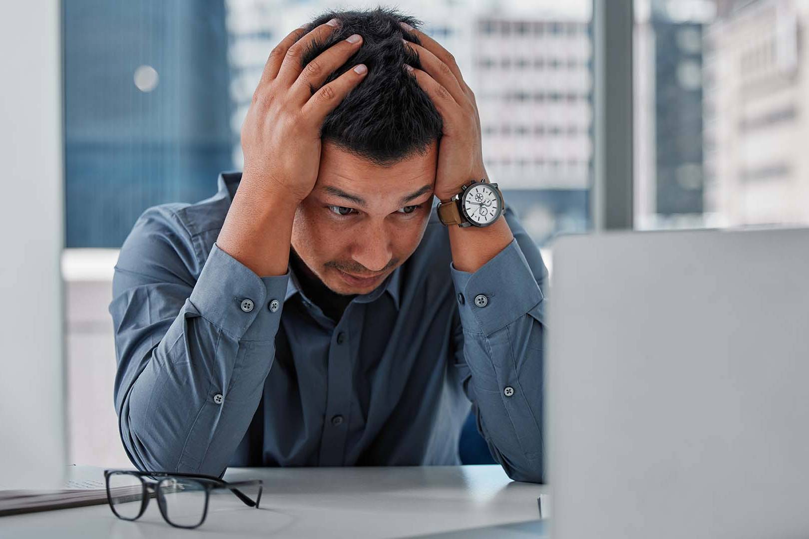 Stressed venture capitalist with head in hands at high-rise office desk