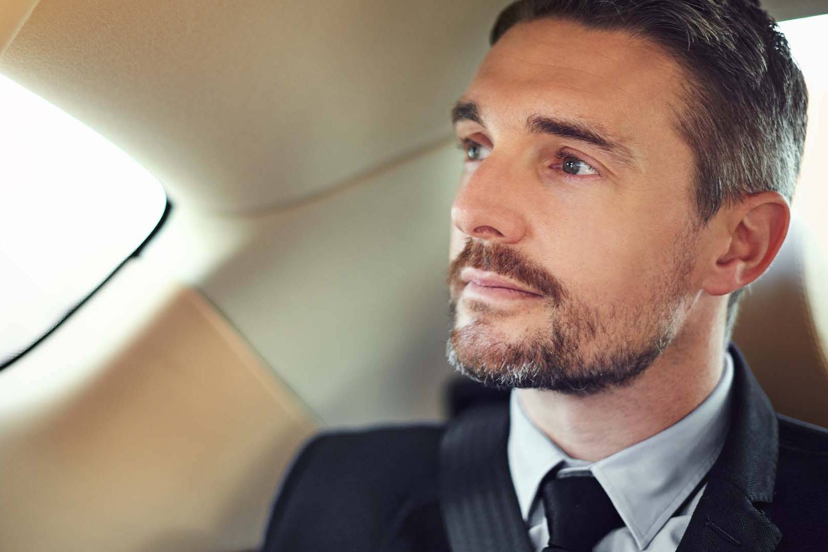 Executive leader in business attire looking contemplative in private jet, representing the mental exhaustion from constant high-stakes decision-making