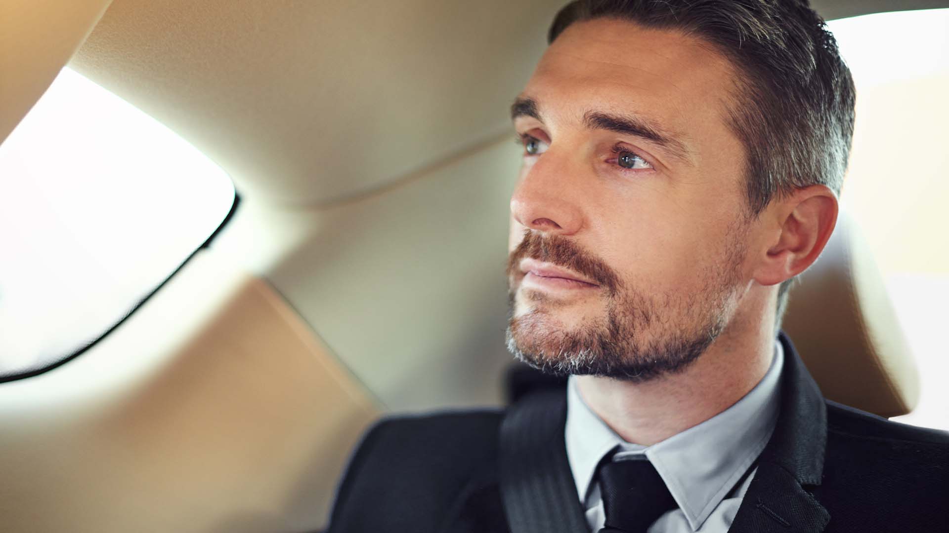 Executive leader in business attire looking contemplative in private jet, representing the mental exhaustion from constant high-stakes decision-making