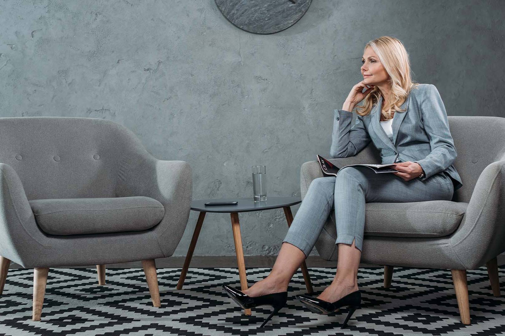 Professional therapist in business attire sitting in modern therapy office with notebook, representing specialized burnout treatment for San Diego entrepreneurs