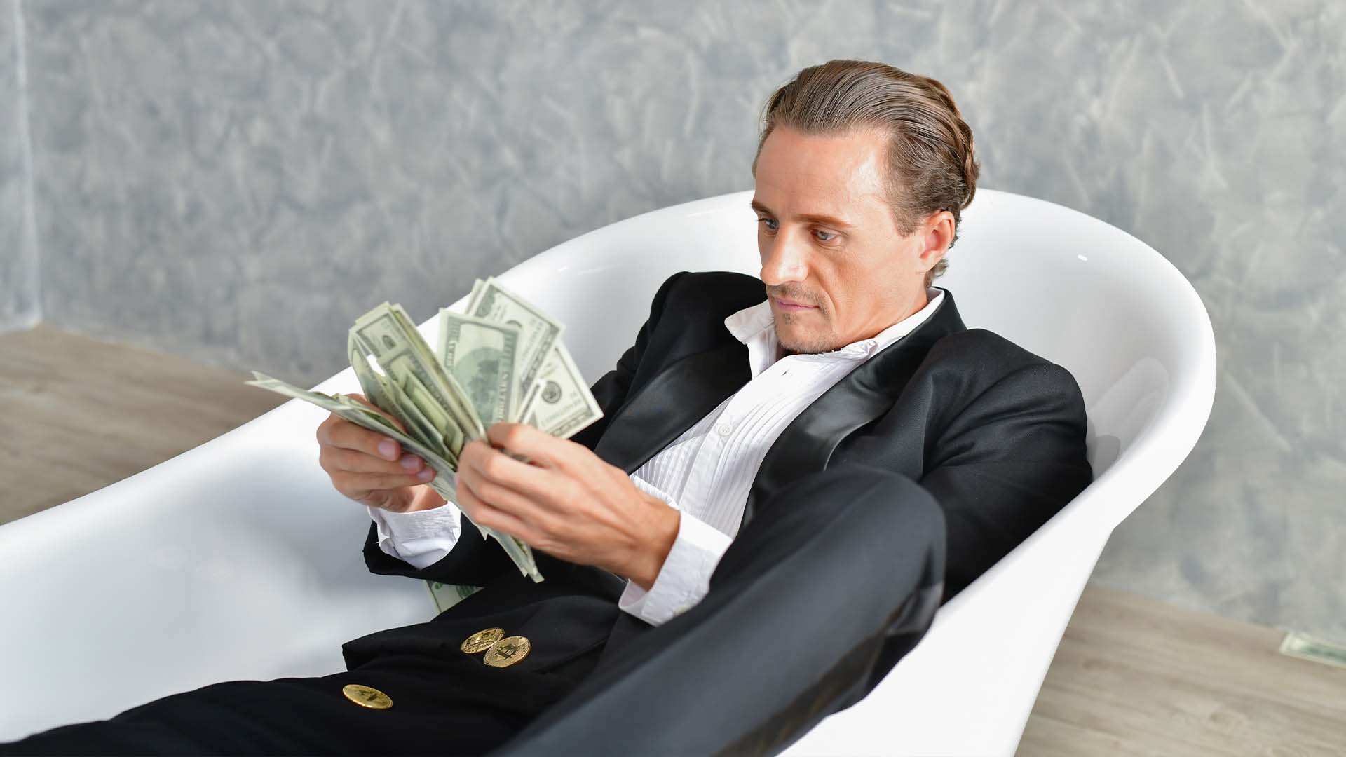 Sophisticated man in tuxedo counting cash while lounging in a bathtub