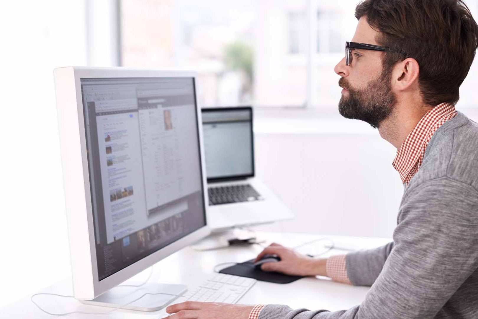 Tech founder working intensely at dual monitor setup in casual office attire, representing the intense focus and mental demands facing California technology entrepreneurs
