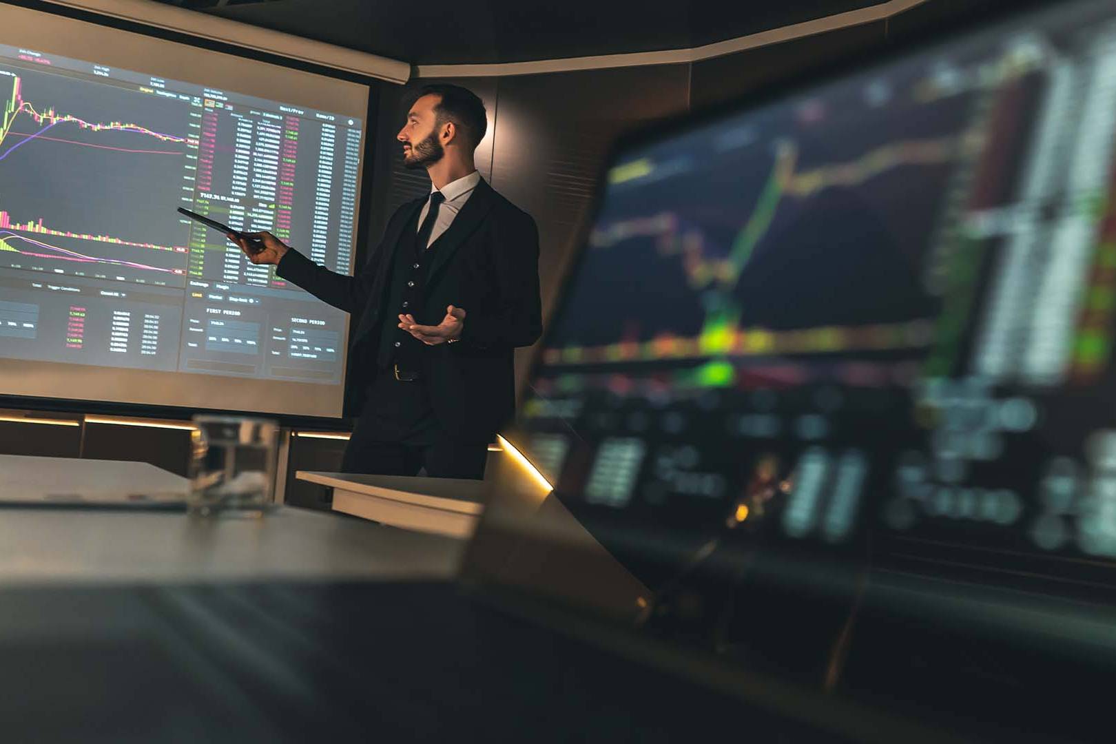 Tech founder in business suit monitoring multiple trading screens with stock market data during IPO process, representing the intense pressure of taking a company public