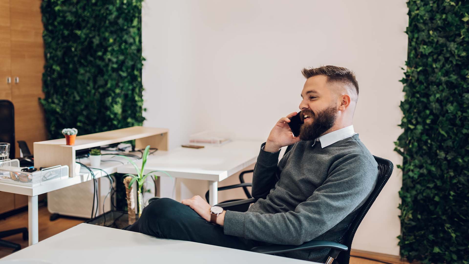 Wealth manager on phone in modern office managing client concerns, representing the emotional burden of stewarding others' financial security and portfolios