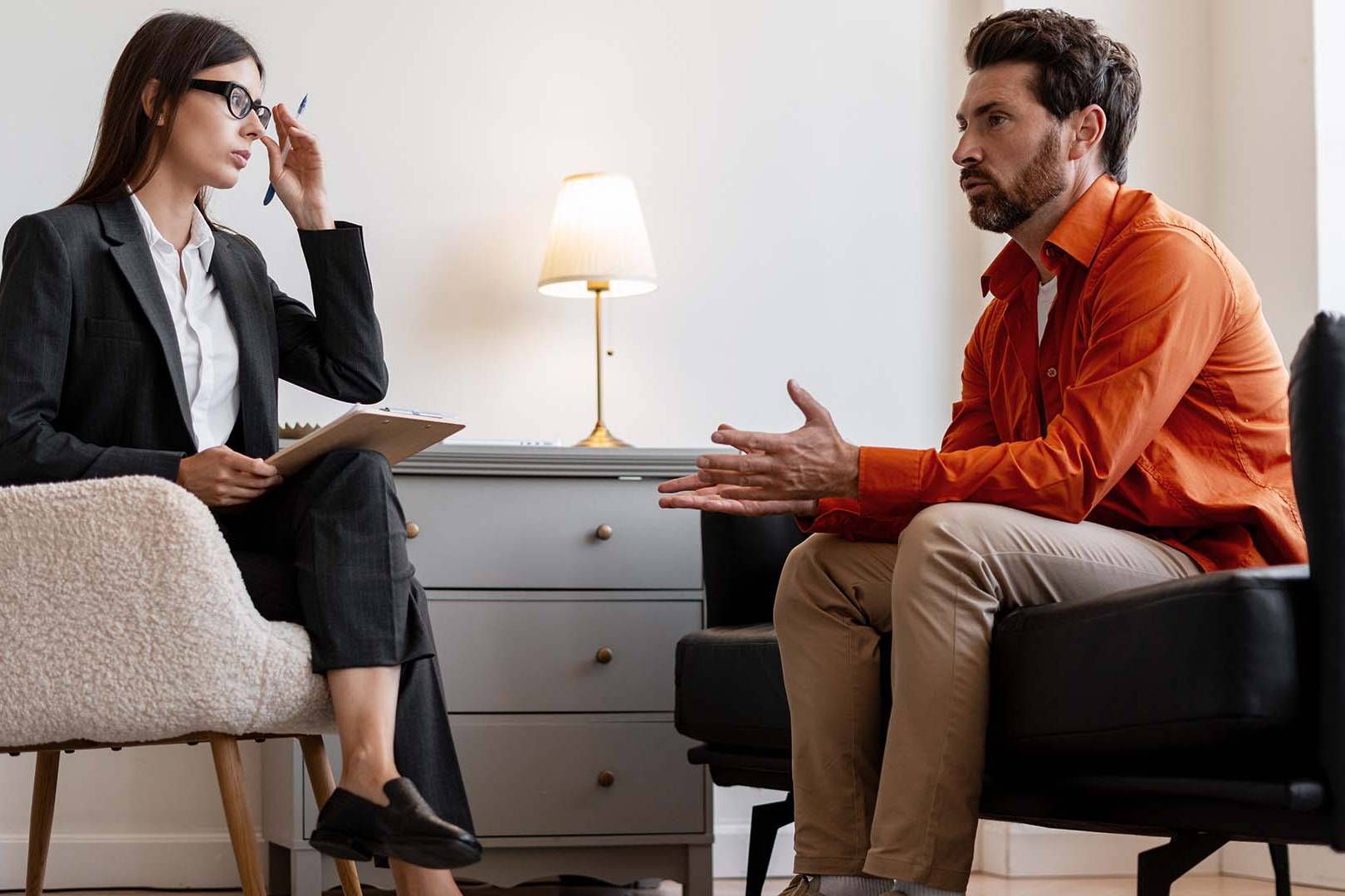 Therapist in suit consulting with male client in casual attire during session