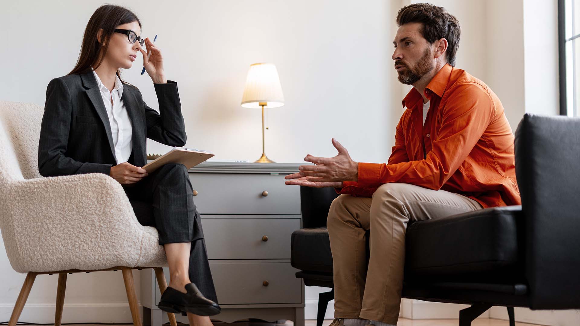 Therapist in suit consulting with male client in casual attire during session