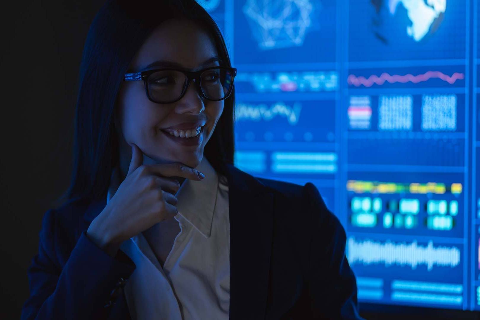 Female tech leader in professional attire with data screens, representing women navigating gender-specific career barriers and leadership challenges in technology industry
