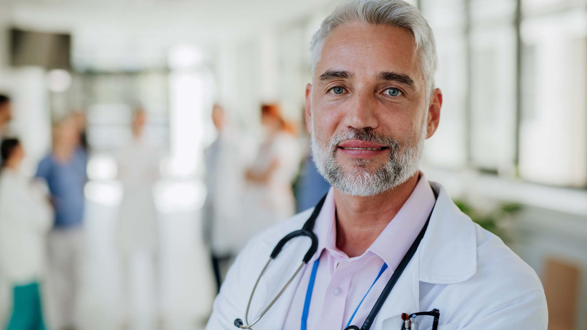 Mature male physician with grey hair and beard representing compassion fatigue in healthcare.