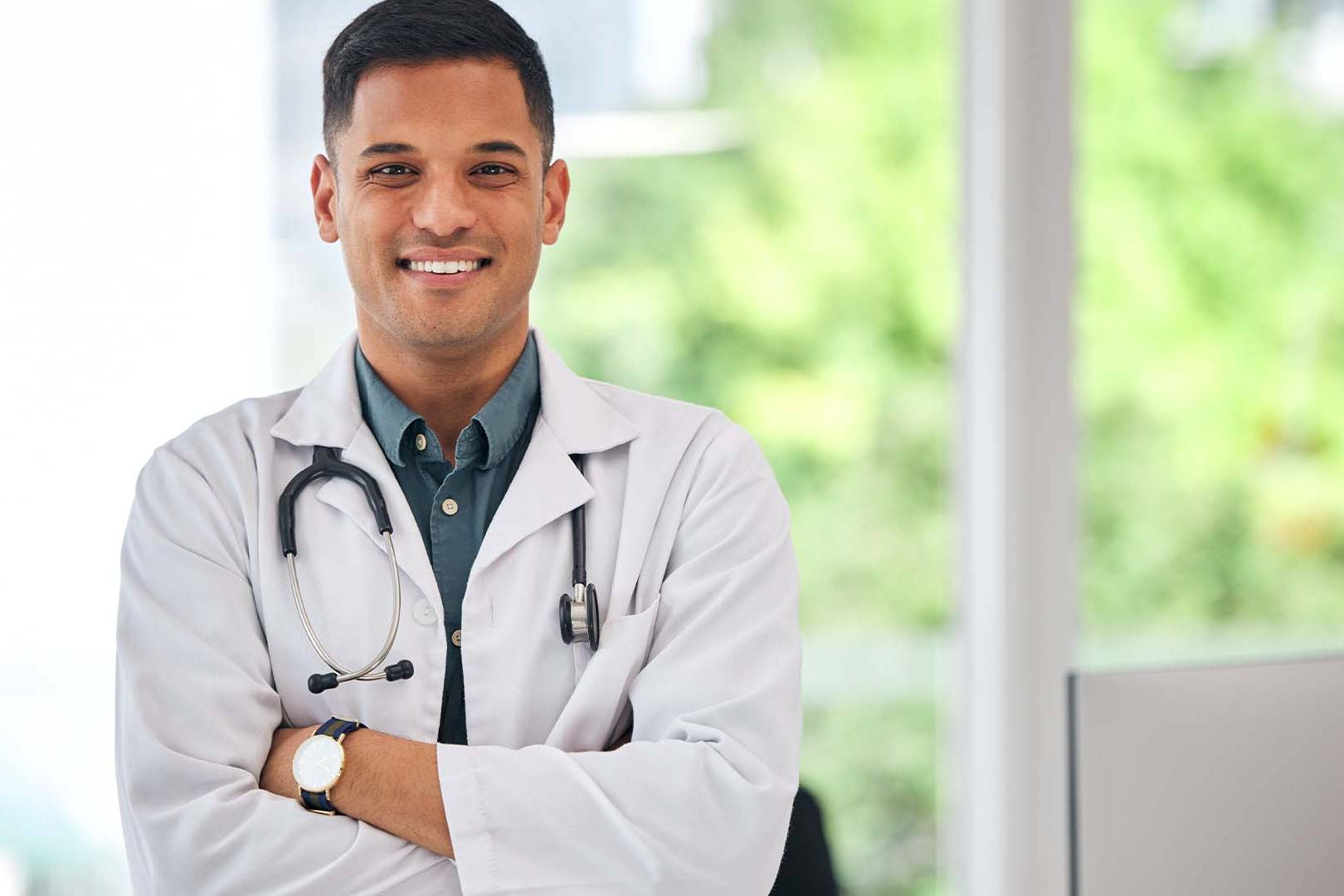 Confident physician in white coat with stethoscope in office
