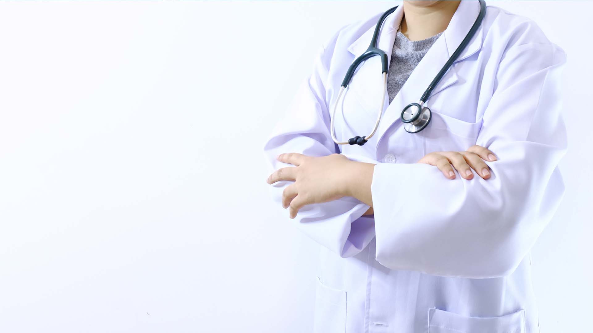 Healthcare professional in a white coat with arms crossed, representing the isolation of Second Victim Syndrome.