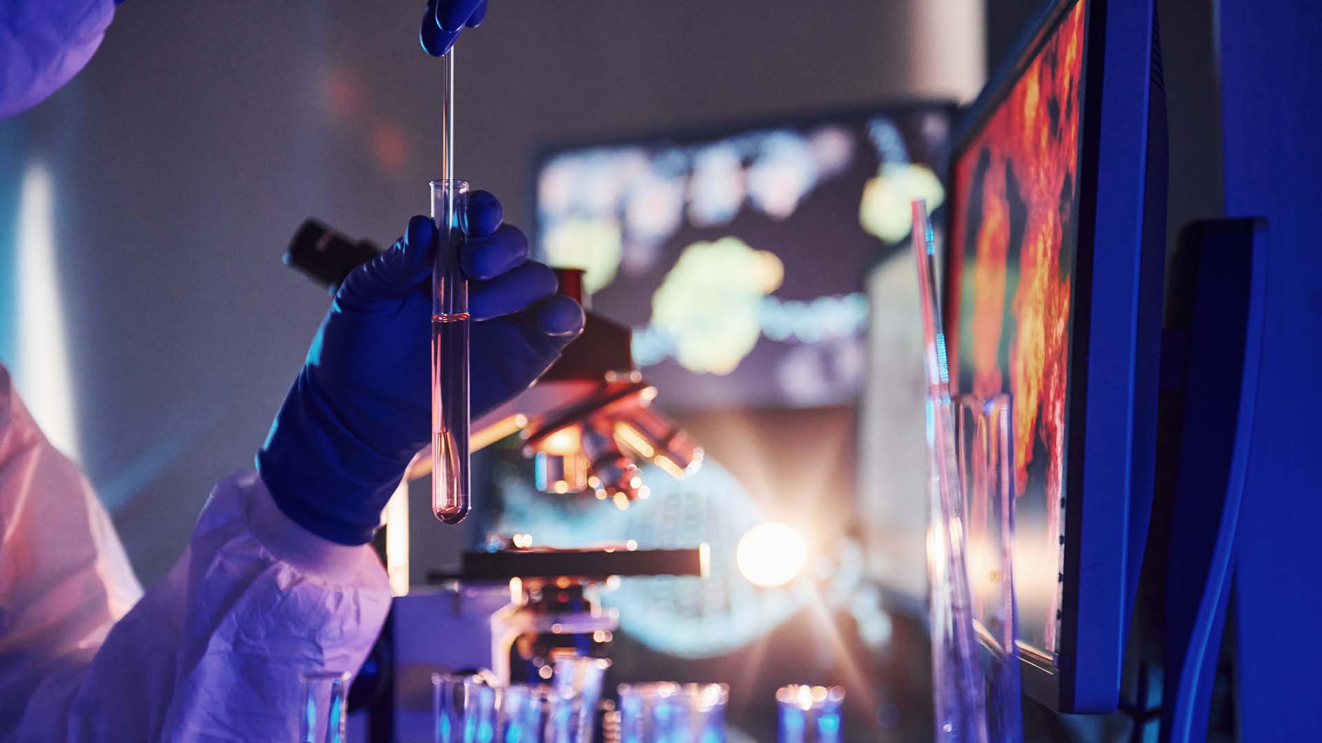 A gloved hand carefully dispensing liquid into a test tube in a dark, high-tech laboratory.