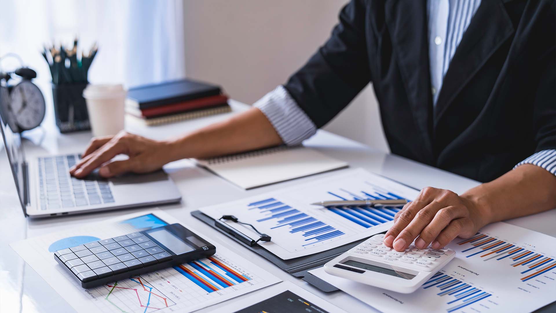 Professional forensic accountant analyzing complex financial charts and data at a desk.