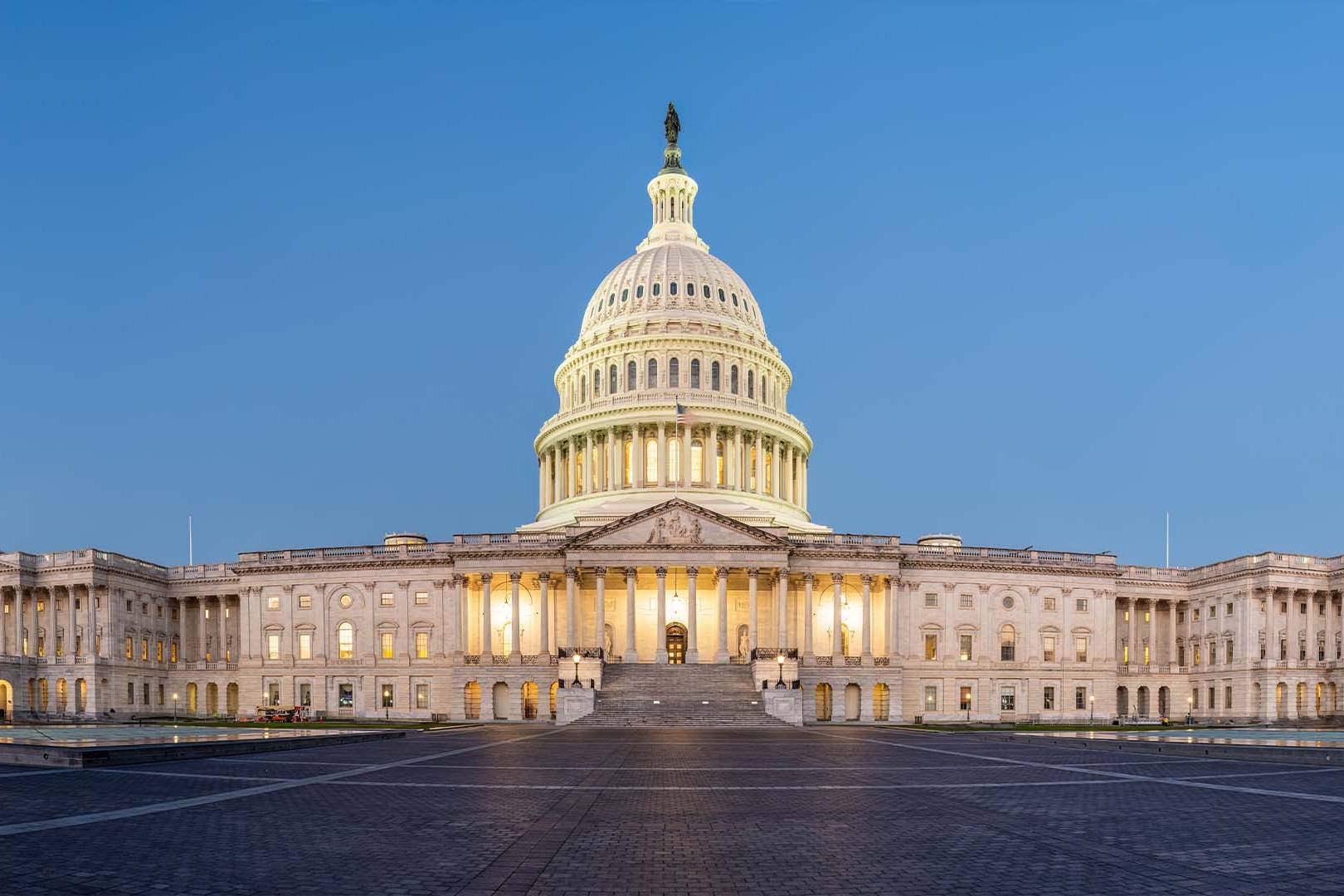 The illuminated United States Capitol building at twilight representing the high-stakes environment of government contracts.