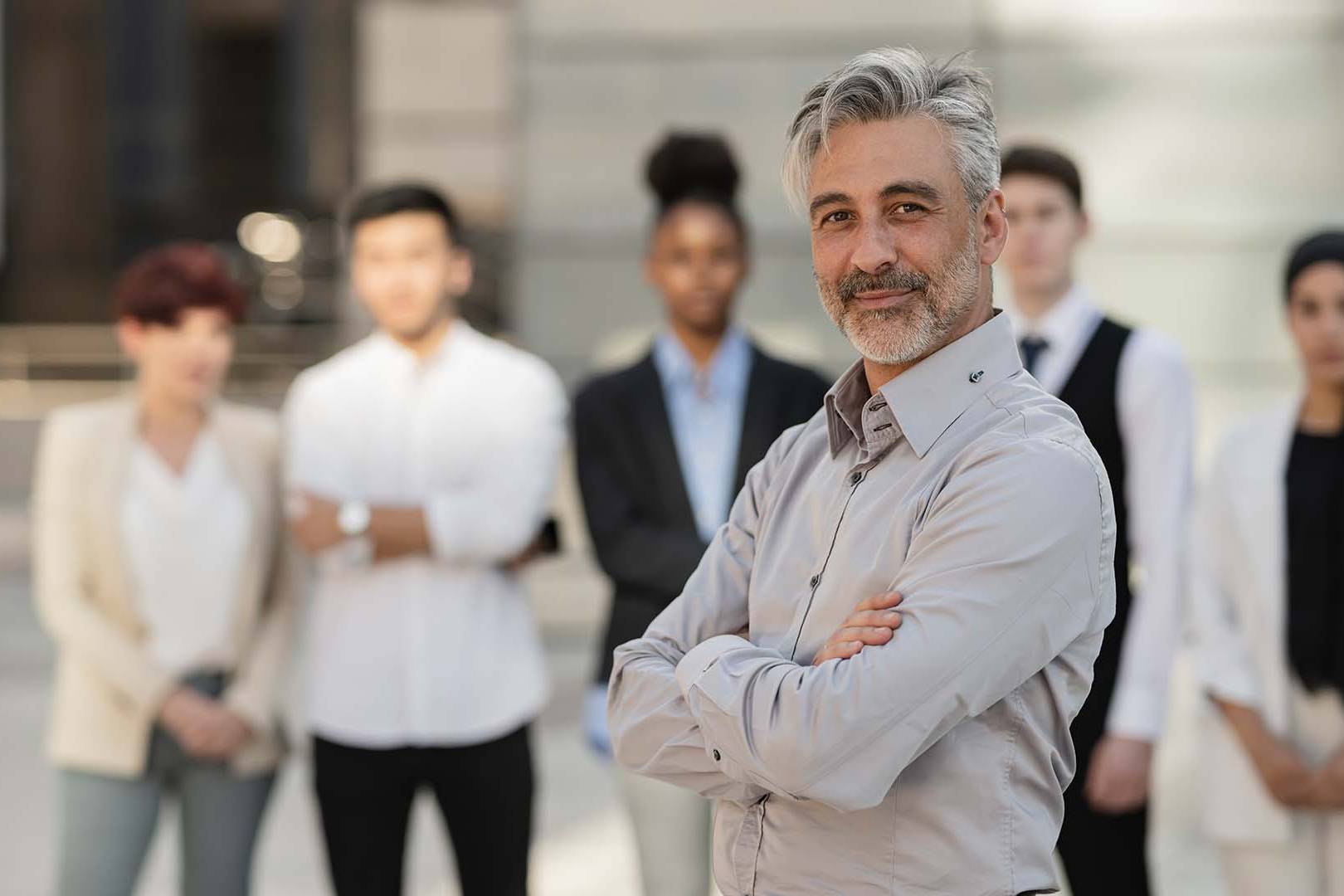 Confident male institutional sales leader standing in front of his diverse corporate team.