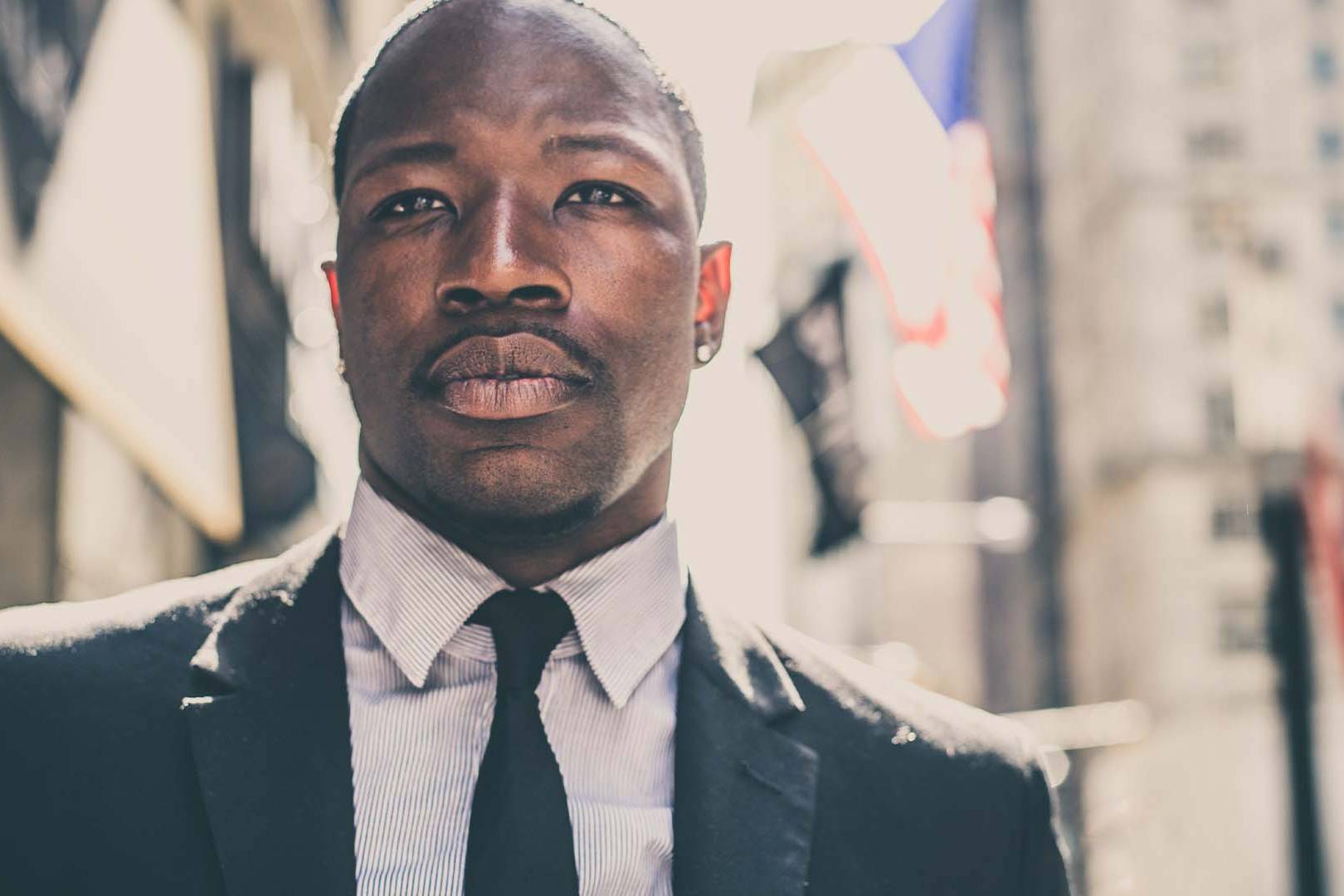 Confident male sports agent in a suit standing in a city street representing therapy for high-stakes professionals.
