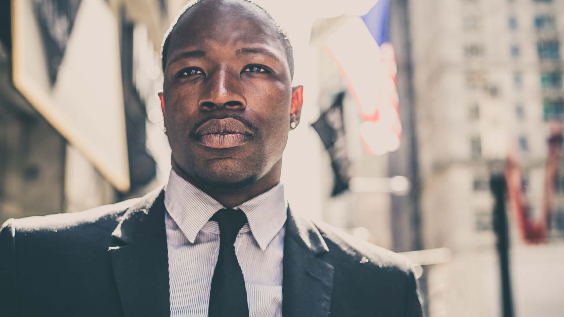 Confident male sports agent in a suit standing in a city street representing therapy for high-stakes professionals.