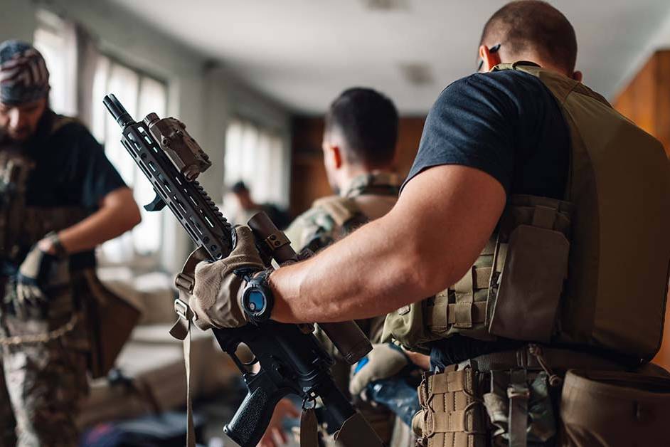 Three military special operations personnel in tactical gear preparing weapons in a staging room, featured image for the article Therapy for Active-Duty Special Operations Officers.