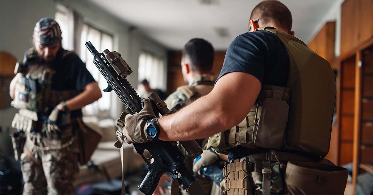 Three military special operations personnel in tactical gear preparing weapons in a staging room, featured image for the article Therapy for Active-Duty Special Operations Officers.