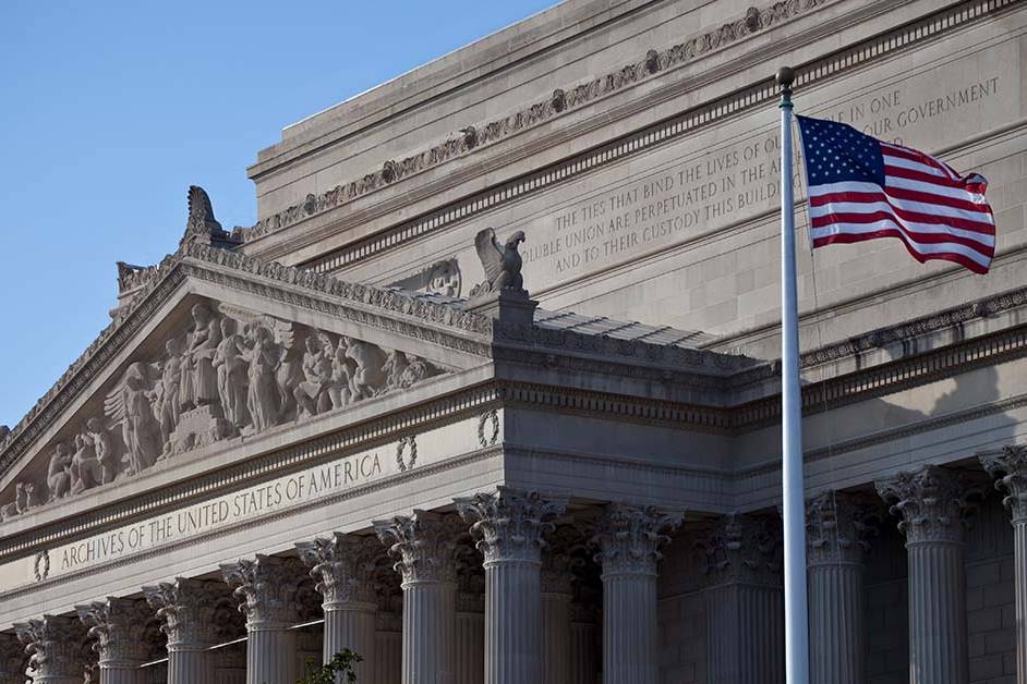 The neoclassical facade of the National Archives building with an American flag flying in the foreground, featured image for the article Therapy for Attorneys With State Bar Reporting Concerns.