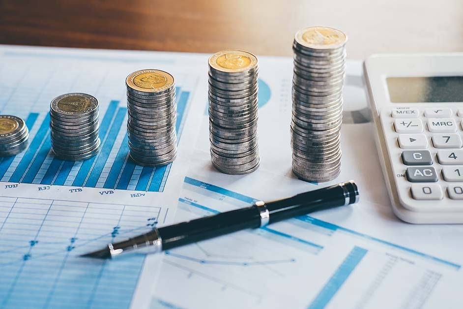 Ascending stacks of coins, a black pen, and a calculator resting on printed financial charts, featured image for the article Therapy for Big Four Accounting Partners.