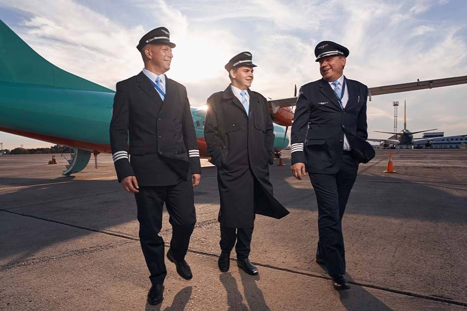 Three pilots in uniform walking together on an airport tarmac at sunset, featured image for the article Therapy for Corporate Jet Pilots. Option 2 (Keyword Focused): Professional aviation crew walking near an aircraft representing mental health therapy and burnout support for corporate jet pilots.