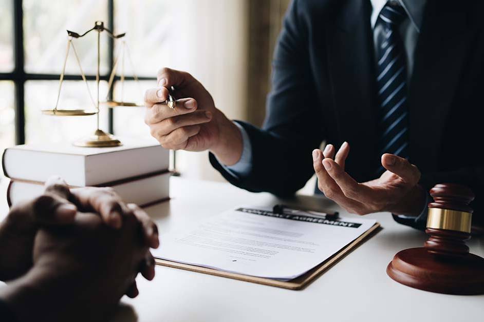 Two professionals discussing a contract agreement at a desk with a gavel and scales of justice, featured image for the article Therapy for DC Big Law Attorneys.