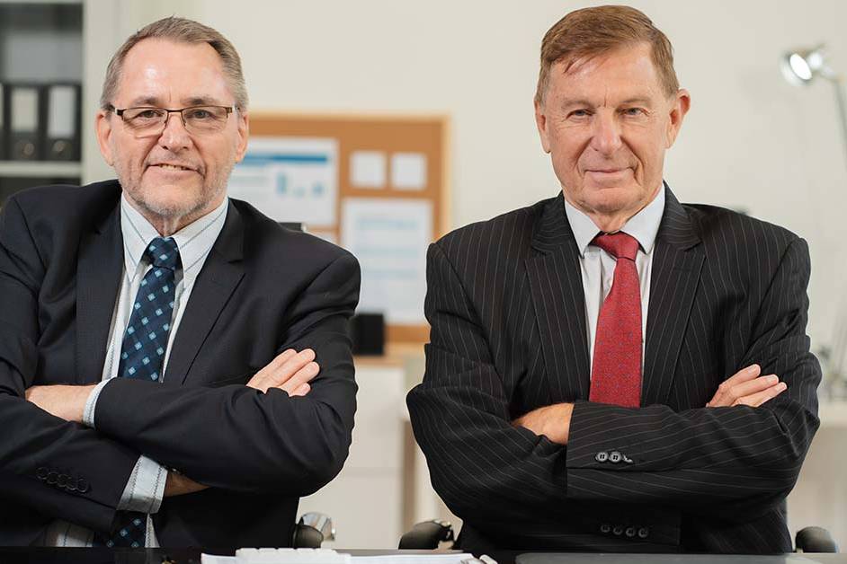 Two senior male financial executives in suits sitting with arms crossed in an office setting, featured image for the article Therapy for Dallas Hedge Fund and Asset Manager Principals.