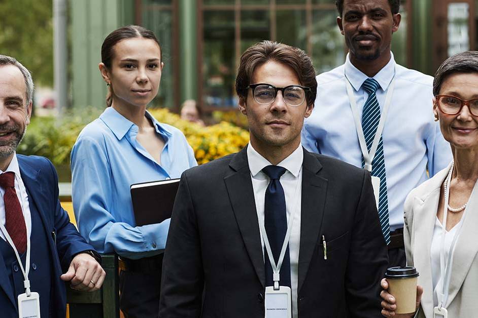 A diverse group of five professionals wearing ID badges standing together outdoors, featured image for the article Therapy for Federal Employees and SF-86 Question 21 Concerns.