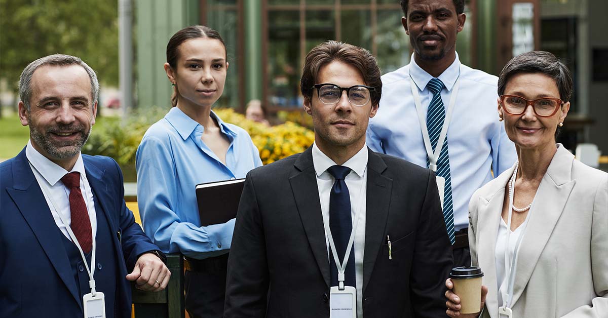 A diverse group of five professionals wearing ID badges standing together outdoors, featured image for the article Therapy for Federal Employees and SF-86 Question 21 Concerns.